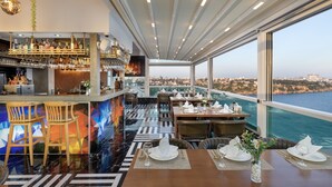 Un restaurante con bar, asientos y vistas al mar.