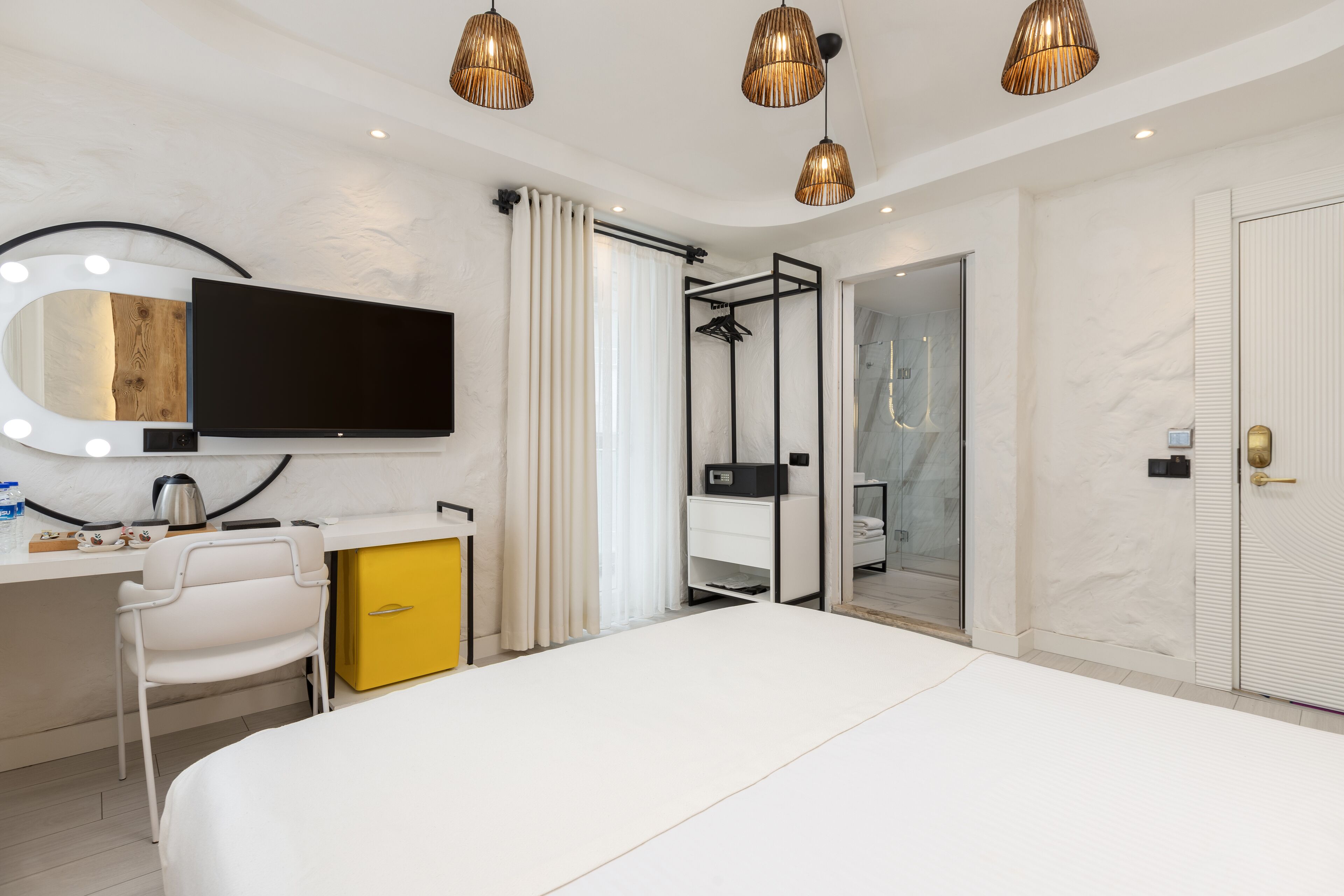 A modern bedroom with a bed, a vanity with a mirror, a shower, and a wardrobe.