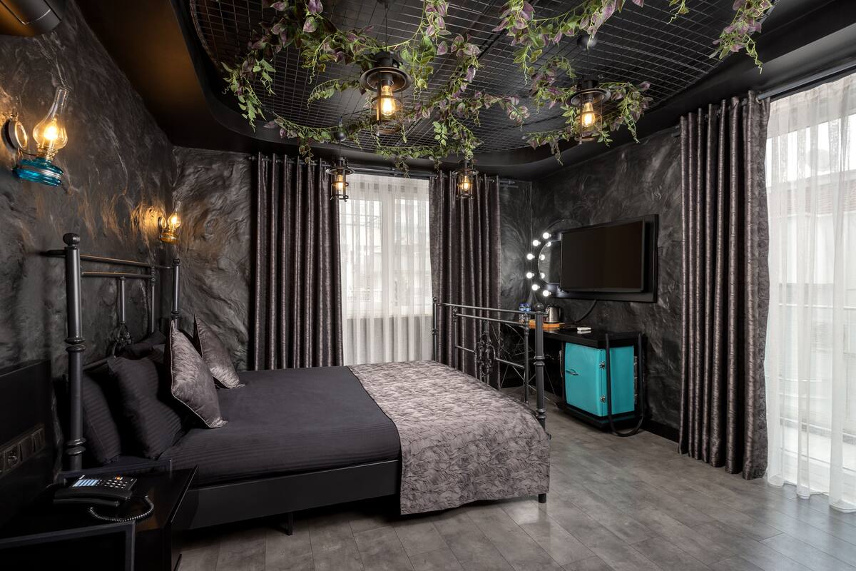 A modern bedroom with a bed, a vanity with a mirror, and a television on the wall.