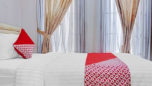 A hotel room with a large bed, white bedding, and red and white patterned pillows. - Capital O 90558 House Of Livina (Jakarta)