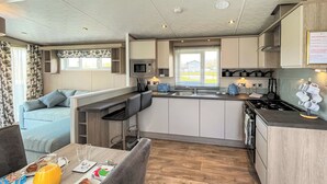 Une cuisine moderne dotée d’un îlot central, d’un coin repas avec un canapé et d’aliments pour le petit-déjeuner disposés sur la table.