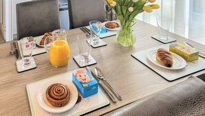 Une table mise pour le petit-déjeuner avec des croissants, un pichet de jus et un vase de tulipes.