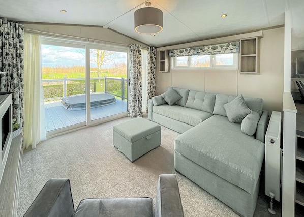 A modern living room with a sofa, ottoman, and a sliding glass door leading to a balcony.