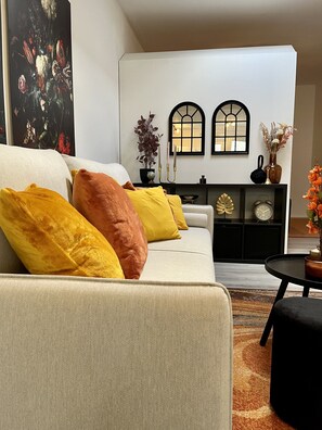 A living room with a sofa, cushions, a side table, a fireplace, and wall-mounted decor. - Fireball: Luxury Loft | Spa | Workspace | Balcony (Bad Staffelstein)