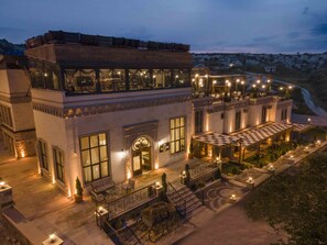 Un hotel de varios pisos con asientos al aire libre y vistas del paisaje circundante.