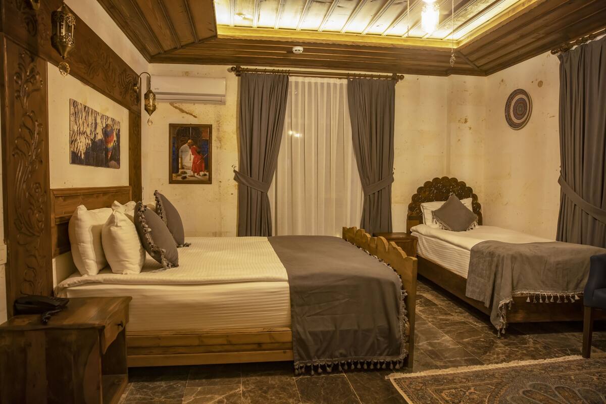 Una habitación con dos camas, cabeceros de madera, una mesita y un espejo.