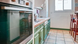 Une cuisine équipée d’un four encastré, d’un évier et de meubles de rangement verts.