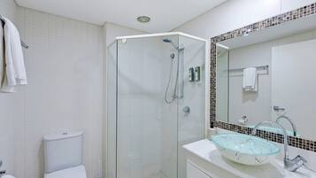 Un bagno moderno con doccia vetrata, un water bianco e un lavabo con bacino in vetro.