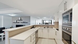 Una cocina moderna con armarios blancos, horno empotrado y una isla grande con fregadero.