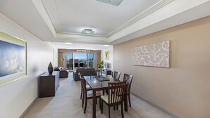 Amplia sala de estar con mesa de comedor, sofás y vistas a través de un ventanal.