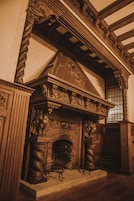 Lareira ornamentada com esculturas detalhadas, um banco de madeira e uma moldura de pedra.