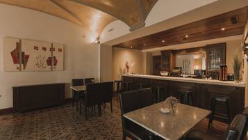 A dining area with a patterned floor, a central table with chairs, and a bar area with stools.