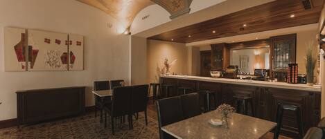 A dining area with a patterned floor, a central table with chairs, and a bar area with stools.