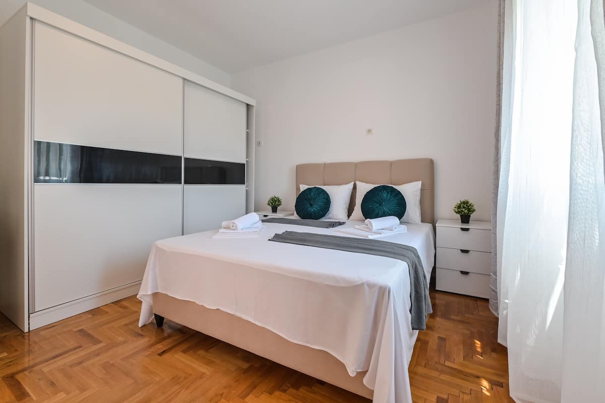 Un dormitorio con una cama, un armario, una mesita de noche y una mesilla.