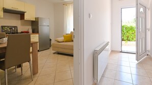 A kitchen with a stove, refrigerator, and dining area. - Apartments Ena (Novalja)