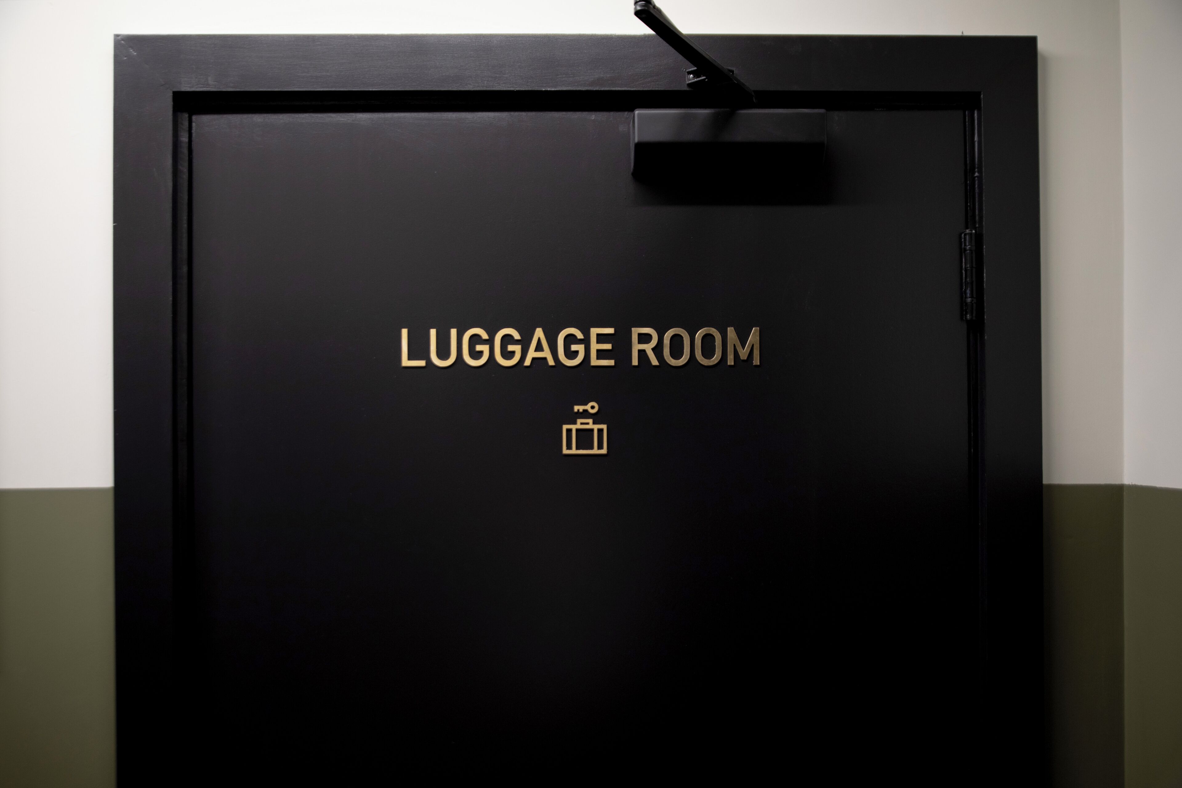 Une porte noire sur laquelle on peut lire en lettres dorées « SALLE À BAGAGES », avec un symbole représentant une valise.