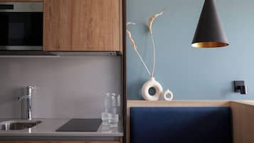 Una cocina moderna con armarios de madera, un lavamanos de acero inoxidable y una lámpara colgante negra.