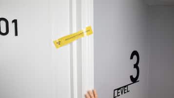 A hand touching a white door with a yellow tape labeled "ridiculously clean standard" and the number "3 LEVEL" on the wall.