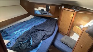 A compact RV interior with a bunk bed, a small seating area, and a kitchenette. - Bateau à Quai (Sainte-Maxime)