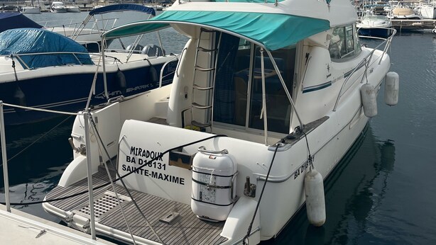 A boat docked at a marina with a covered seating area and a water tank labeled "MIRADOR BA D18131 SAINTE MAXIME". - Bateau à Quai (Sainte-Maxime)