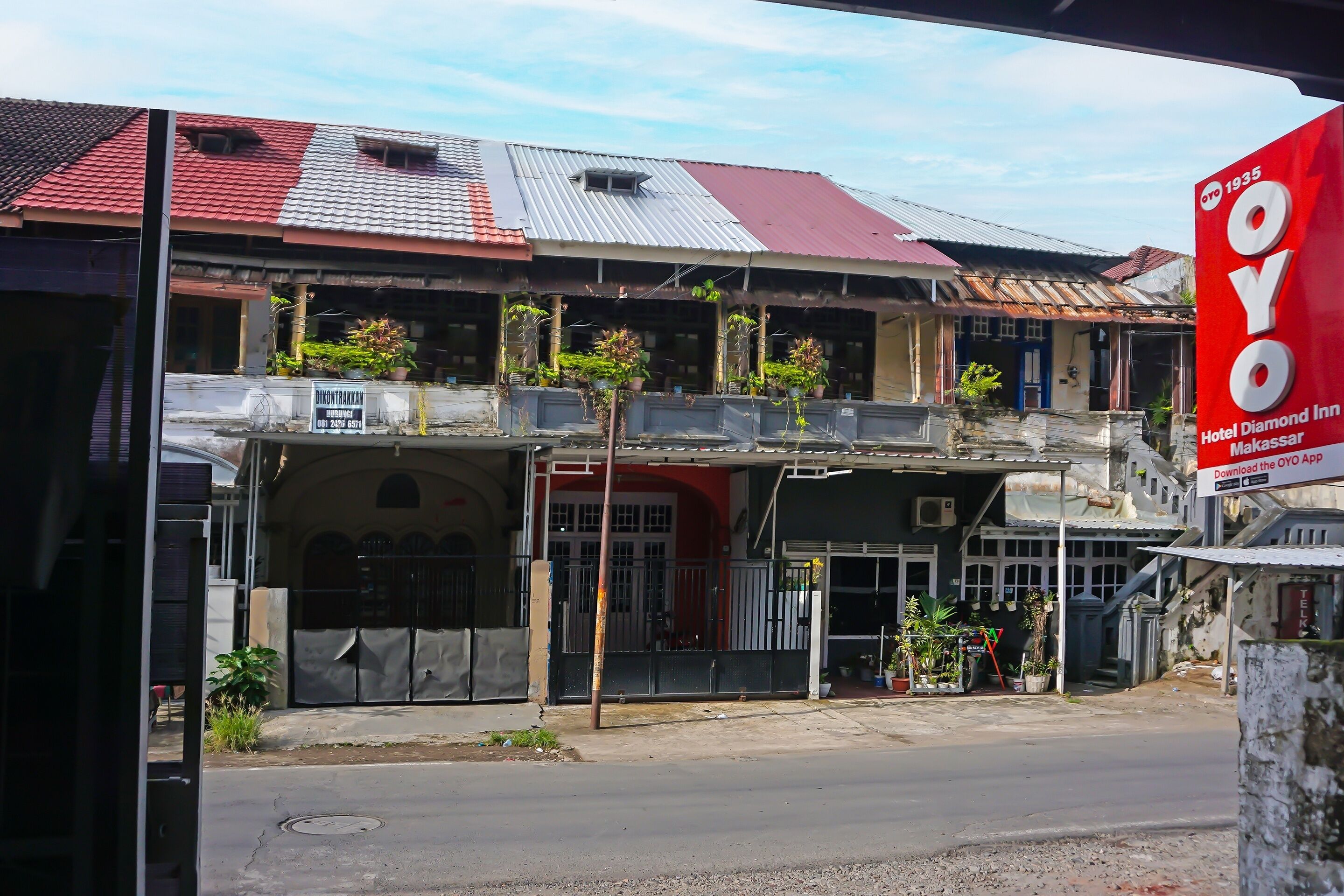 A building with a red and grey roof, a signboard for Hotel OYO, and a gated entrance.