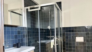 A modern bathroom with a glass-enclosed shower, a white toilet, and a wooden vanity with a mirror. - Penthouse apartment (Šimuni)