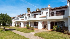 A row of white buildings with red-tiled roofs, numbered 65, 66, and 67, featuring balconies and a central courtyard. - Apartment SON BOU, 67 (Son Bou)