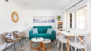 A bright living room with a teal sofa, wicker chairs, a white coffee table, and a white dining table. - Apartment SON BOU, 67 (Son Bou)