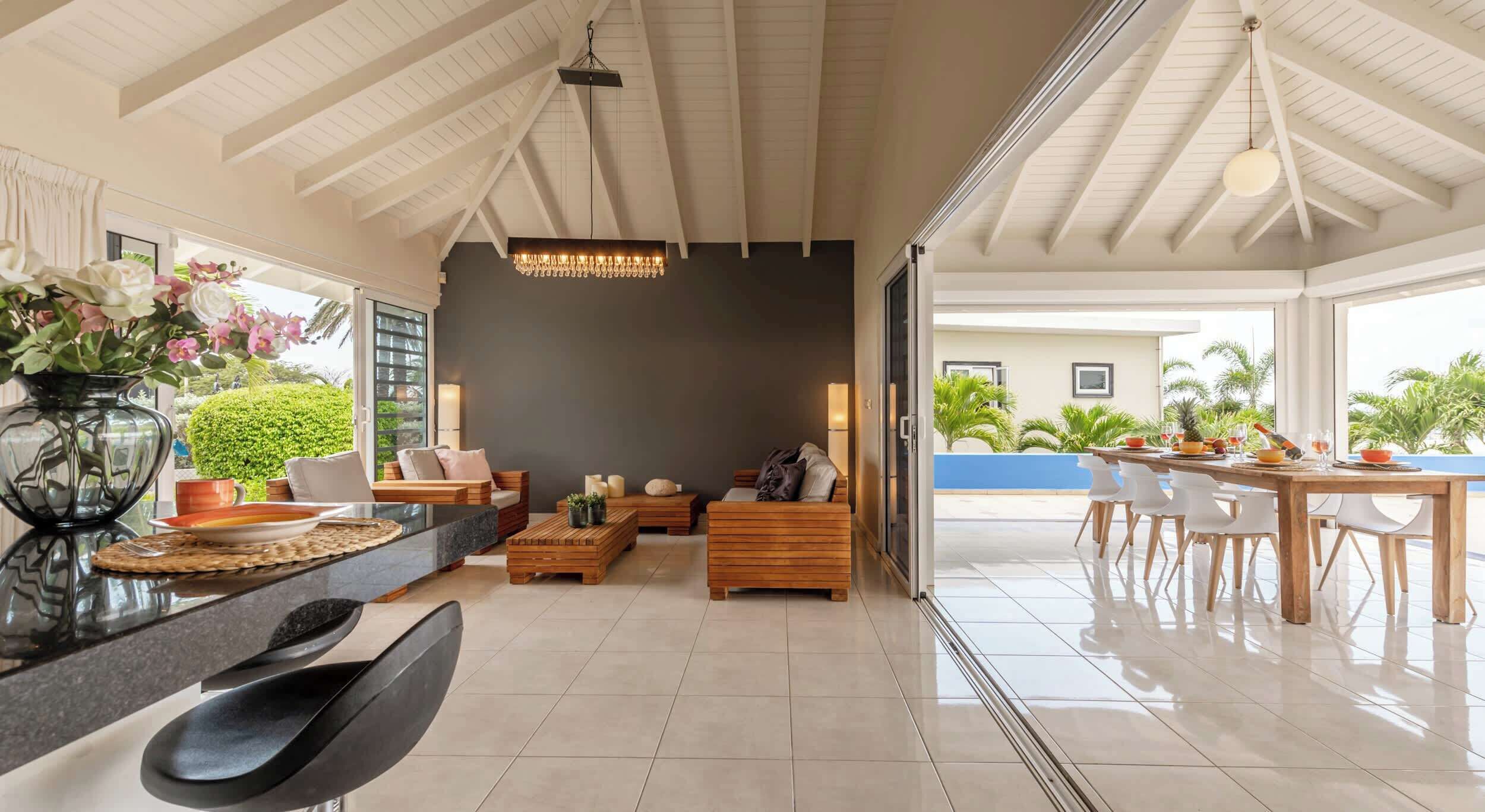 Un vaste espace de vie doté d’un haut plafond, un coin repas avec une table et des chaises, et une vue sur l’extérieur.