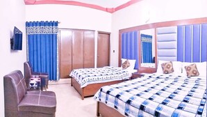A hotel room with two beds, a sofa, a desk, and a wardrobe. - Subhan Palace Guest House (Dubai)