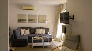 Ein Wohnzimmer mit einer Couch, einem Couchtisch, einem Fernseher und einem Sessel.