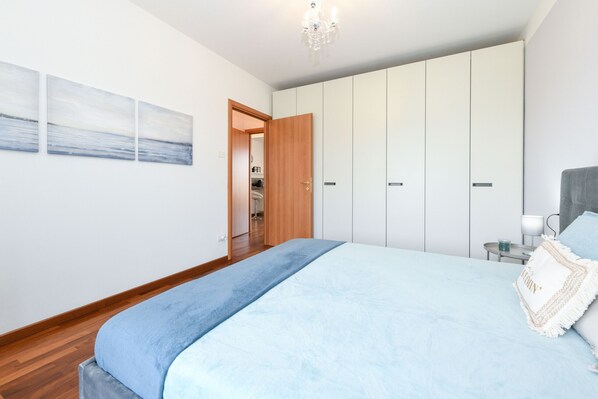 A bedroom with a large bed, a wardrobe, and a nightstand. - Leone: modern apartment in Moniga (Moniga del Garda)