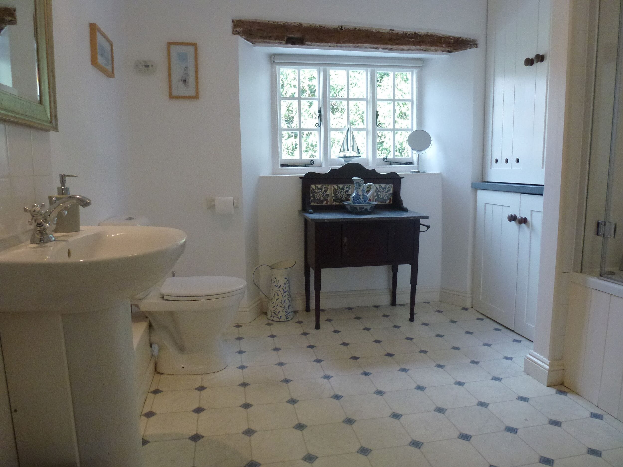 A bathroom with a sink, toilet, and window.