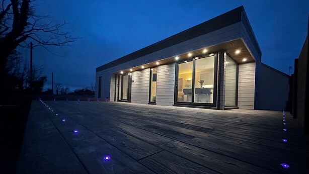 Ein modernes Haus mit großen Glasfenstern und einer Holterrasse.