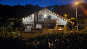 Een houten huis met twee verdiepingen, een balkon, een garage en een klein portaal.