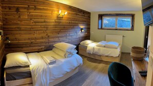 Een gezellige kamer met houten wanden, twee bedden, een raam en een stoel.