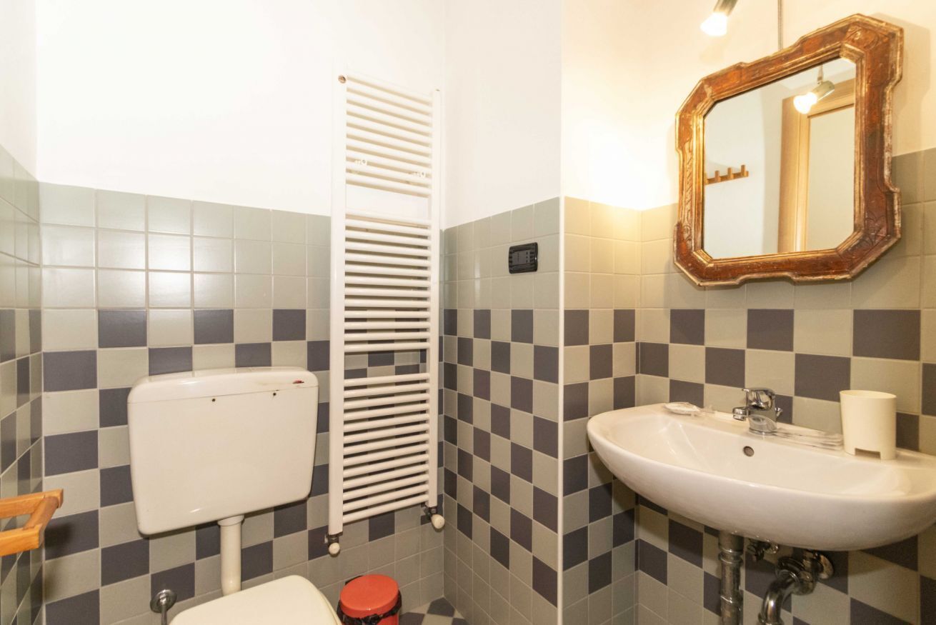 Un bagno con il water, un lavandino, uno specchio e pareti piastrellate.
