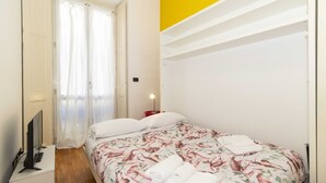 A bedroom with a bed, a TV, a nightstand, and a window with curtains. - GuestHost - Porta Nuova Mini Flat 2 New! (Torino)