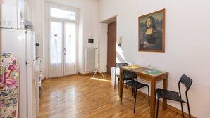 Una habitación con suelo de madera, una mesa de comedor con sillas, un radiador y un cuadro en la pared.