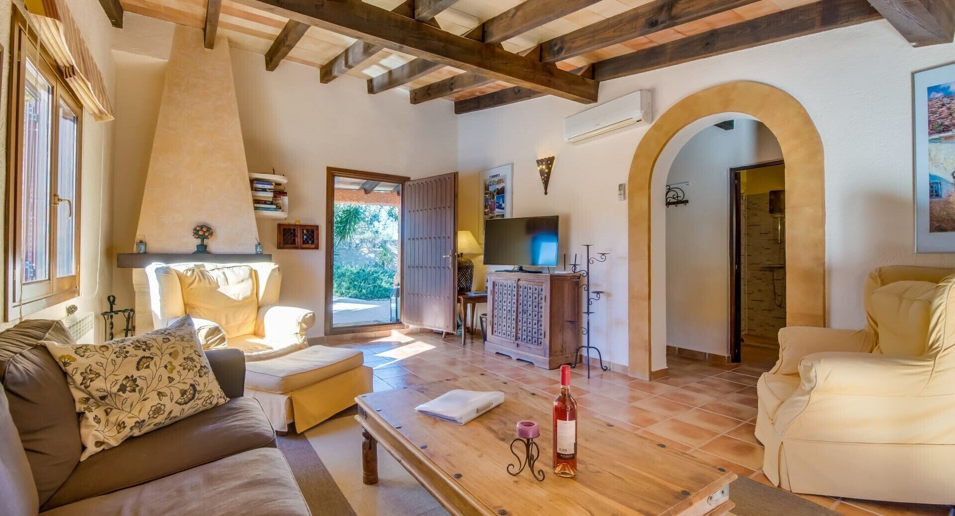 A spacious living room with a wooden ceiling, a sofa, a coffee table, and a TV.