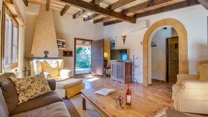 A spacious living room with a wooden ceiling, a sofa, a coffee table, and a TV. - Finca Ferragut - Beautiful Mallorcan finca with pool (main house) (Artá)