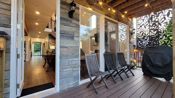 A covered patio with wooden flooring, stone walls, and a grill. - CAN-Luxury cottage by the water (Severn Bridge)