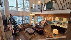 A spacious living area with a high ceiling, a dining table, and a kitchen in the background. - CAN-Luxury cottage by the water (Severn Bridge)
