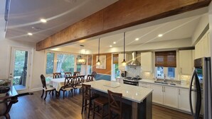 A spacious kitchen with a large island, wooden beams, and pendant lighting. - CAN-Luxury cottage by the water (Severn Bridge)