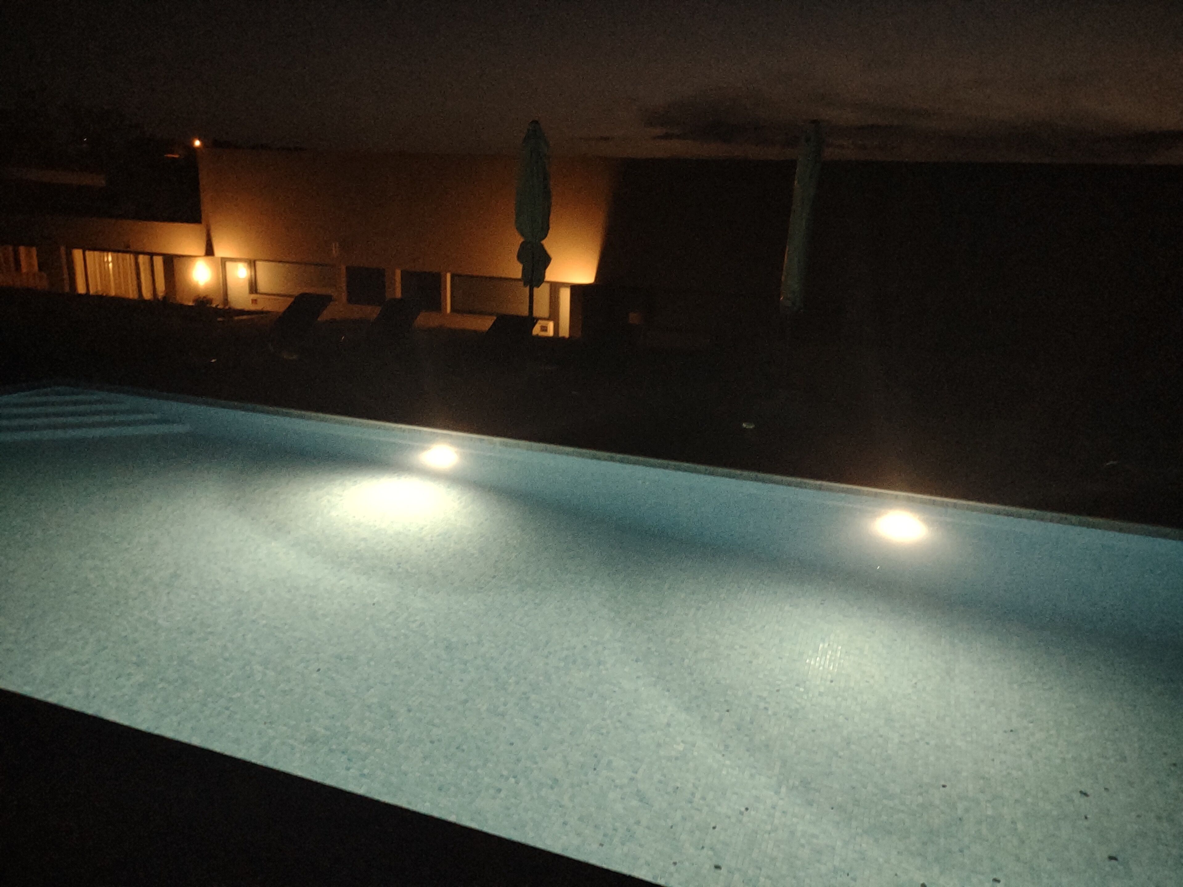 A swimming pool with a tiled floor and two lights on either side.
