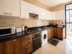 Eine moderne Küche mit Mikrowelle, Toaster, Herd, Spüle und Waschmaschine.