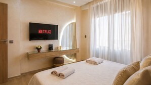 A hotel room with a bed, a TV mounted on the wall, a bedside table with a lamp, and a window with curtains. - Loli Home Agadir - Bay Premium Pool (Agadir)