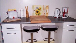 A kitchen with a toaster, a coffee maker, a cutting board, and two bar stools. - Franglais flats (Boulogne-sur-Mer)