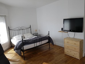 Una camera da letto con un letto, una cassettiera in legno e una televisione a parete.