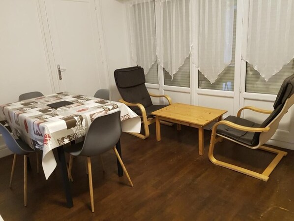 A dining area with a table covered in a patterned tablecloth, two chairs, and a small wooden table. - Franglais flats (Boulogne-sur-Mer)